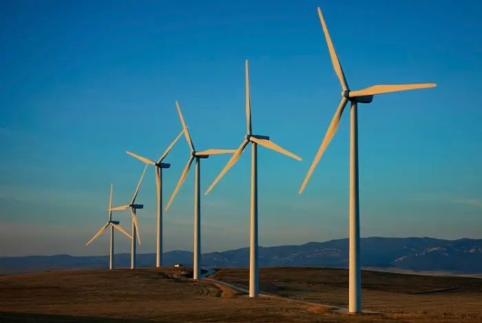 Cover of the JustRE Alliance report Community Ownership in Renewable Energy Models featuring wind turbines in a rural landscape.
